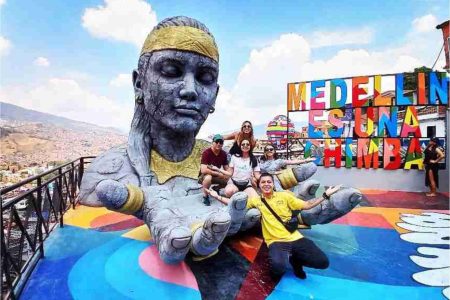 Viajeros posando en el mirador de la Comuna 13, junto a la escultura y el letrero de colores de Medellín