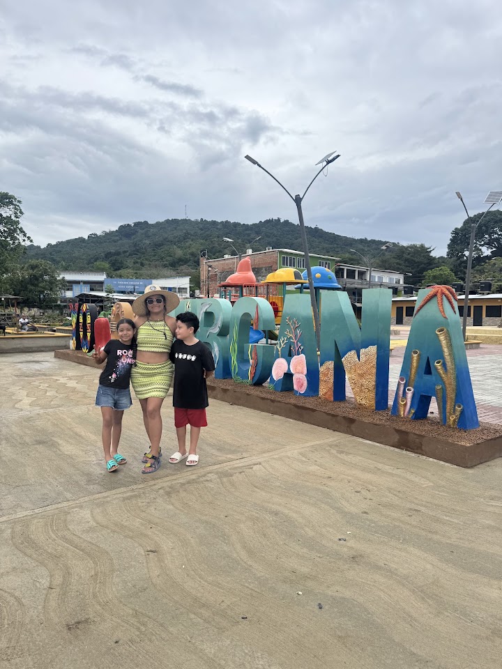 Familia de viajeros frente al letrero de Capurganá