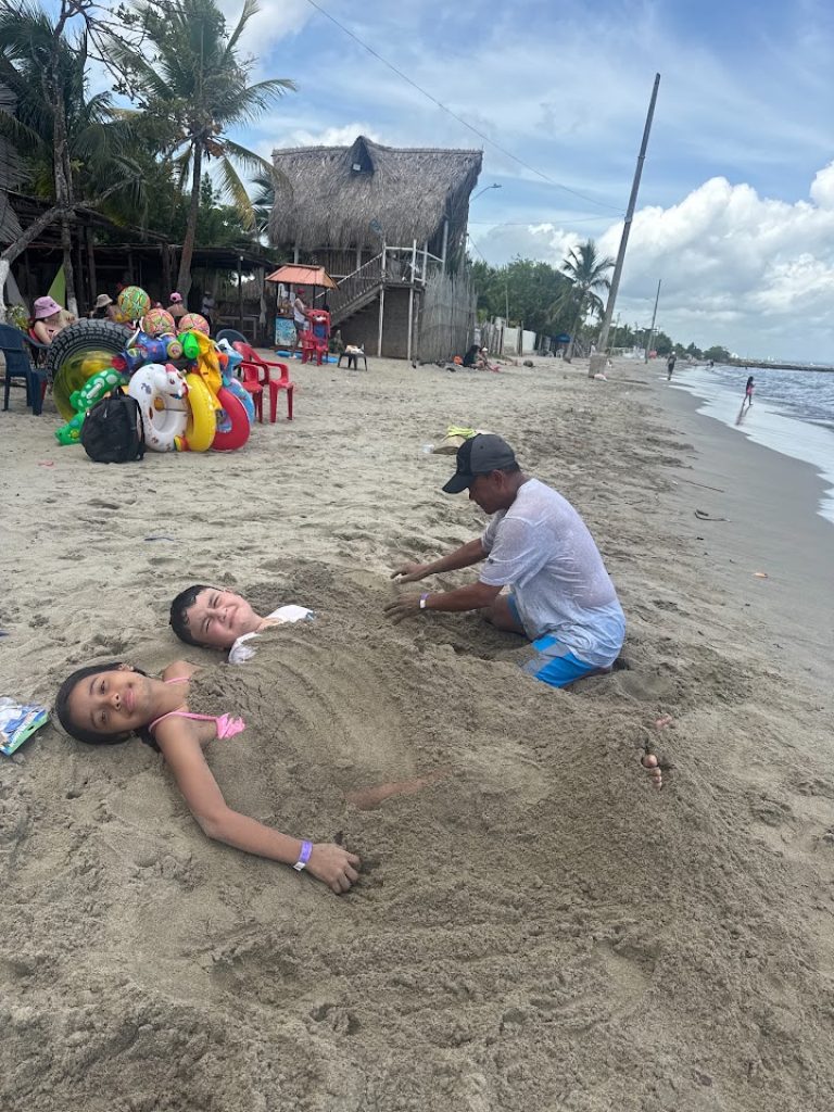 Niños jugando enterrados en la arena durante un plan de playa